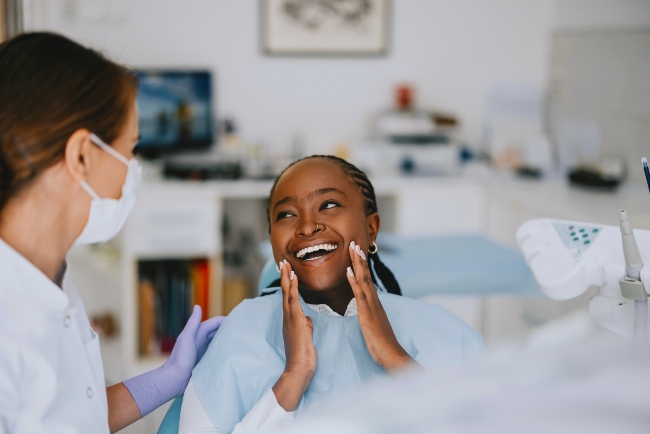 A smiling woman in a dental chair interacting with a dentist after treatment in Monett, MO