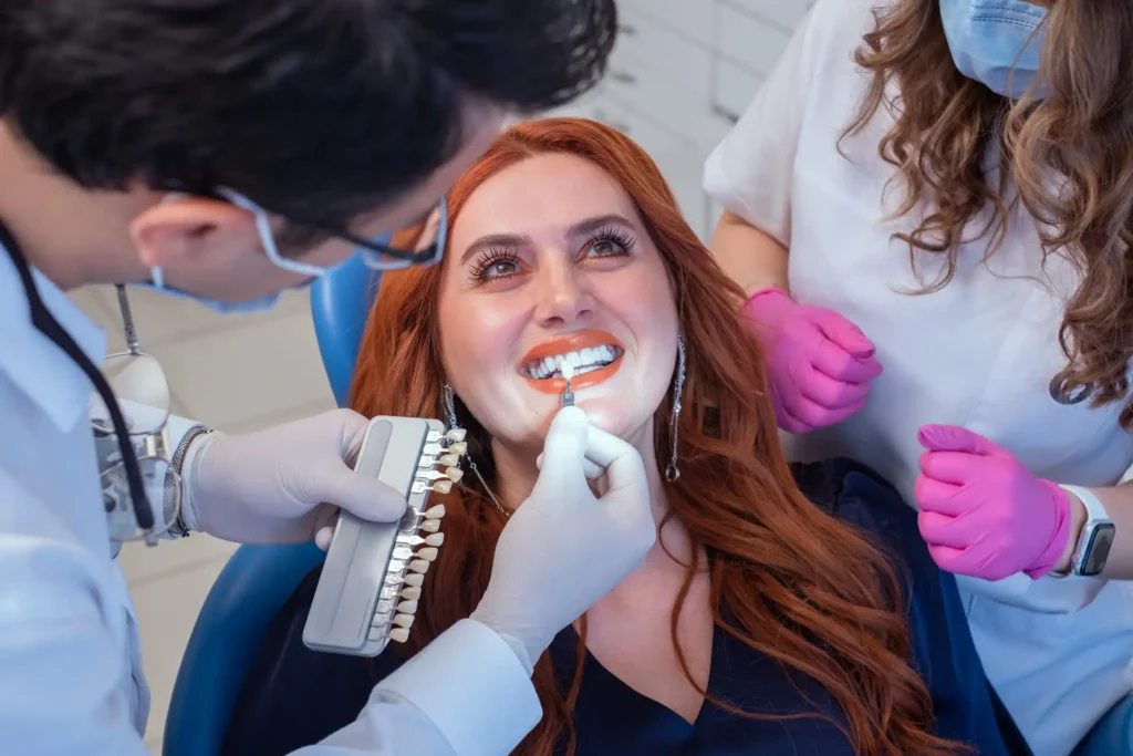 A dentist using a shade guide to match tooth color for porcelain veneers in Monett, MO