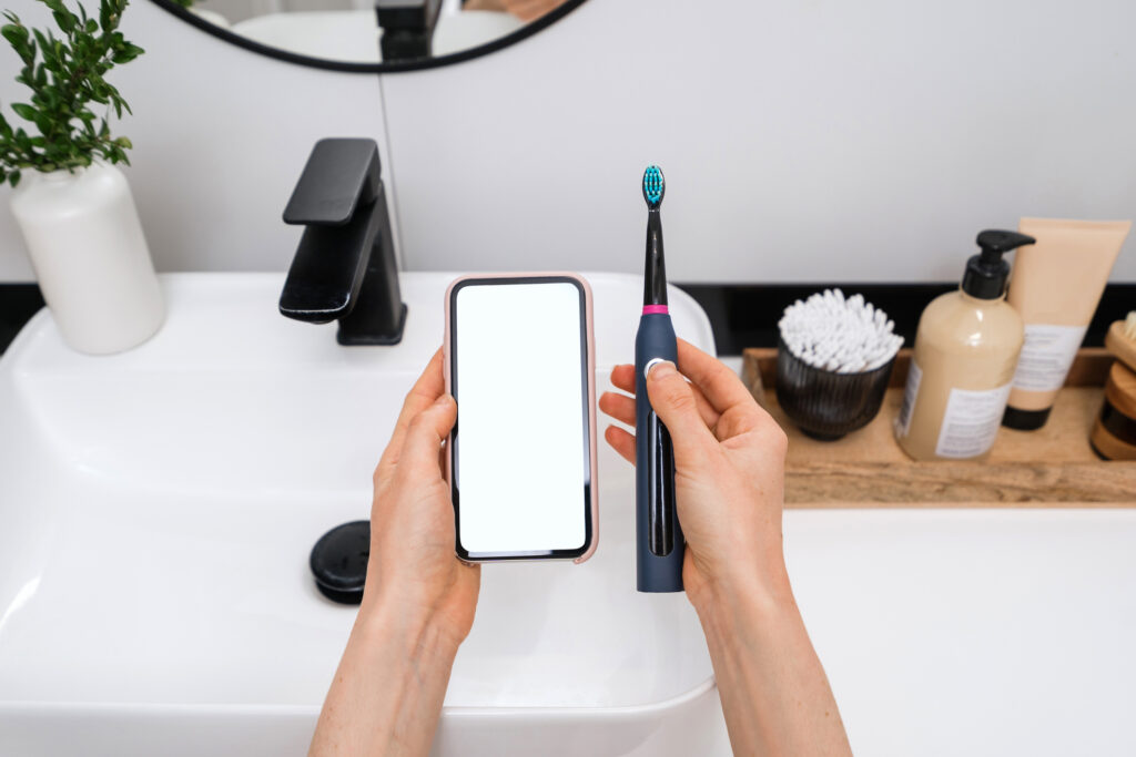 cropped shot of female hand hold wireless connection ultrasonic electric toothbrush with smart phone app, innovative technology