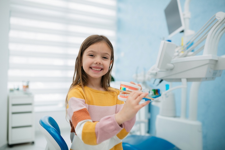Child holding dental model in clinic chair in Monett, MO